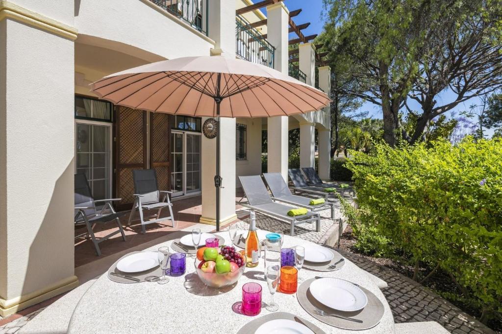 LudoSera - Luxury 3 bedroom apartment with pool, golf,beach的一张桌子,上面放着一碗水果和一把雨伞