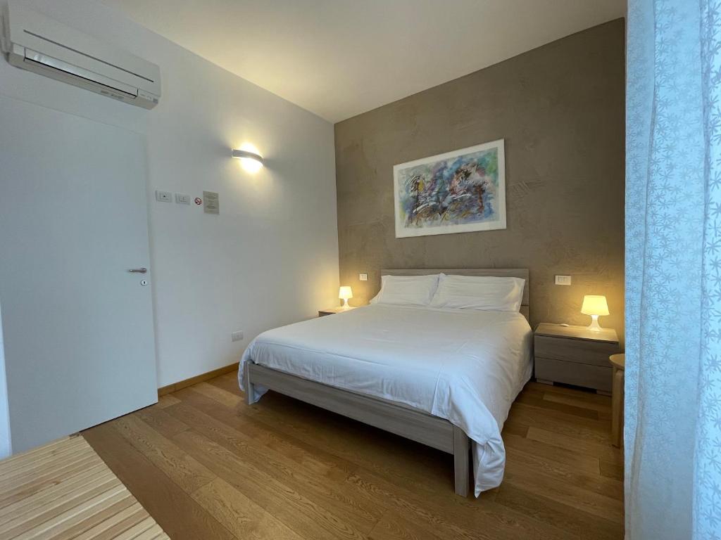 维罗纳Sarah Apartment Verona Fiera的卧室配有一张白色大床和两盏灯。