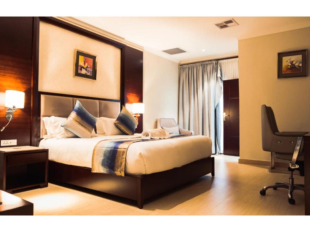 卢萨卡Grand Palace Hotel Lusaka的一间卧室配有一张床、一张桌子和一把椅子