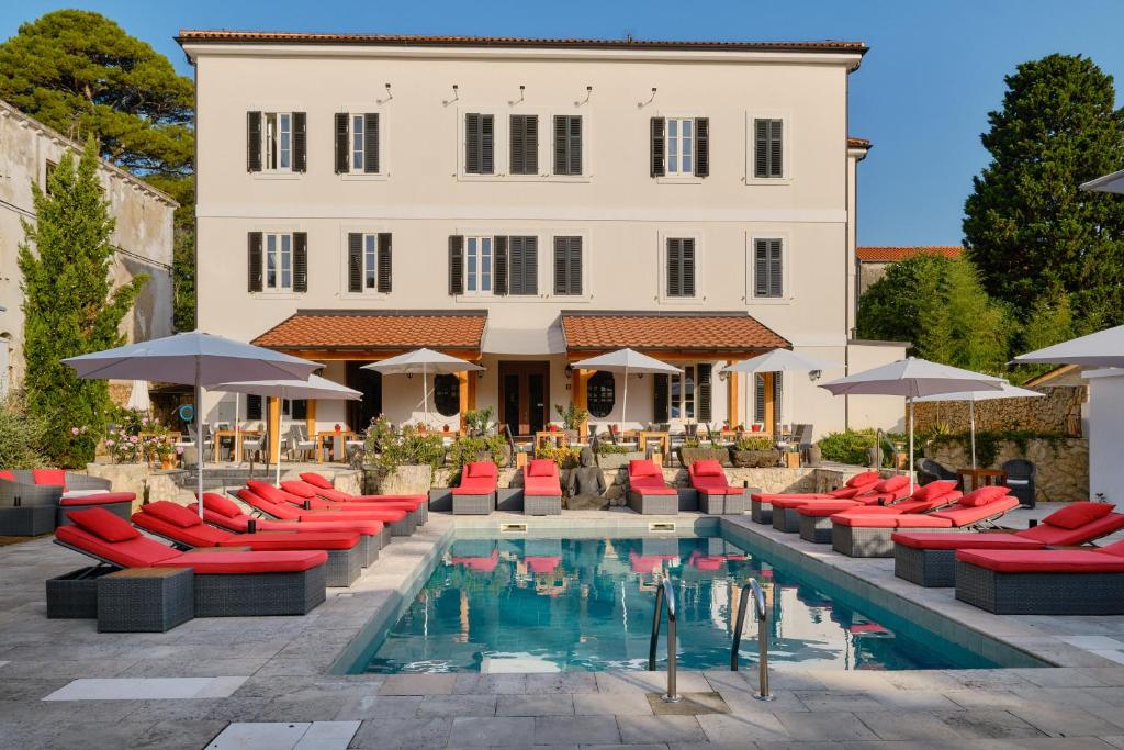 大洛希尼Dolphin Suites的一座带红色椅子的游泳池和一座建筑的酒店