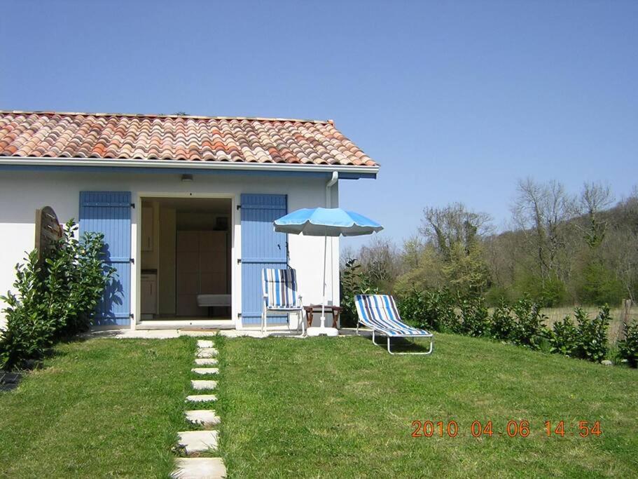 EscosGîte Le Trèfle Studioescos的蓝色的房子,配有椅子和雨伞