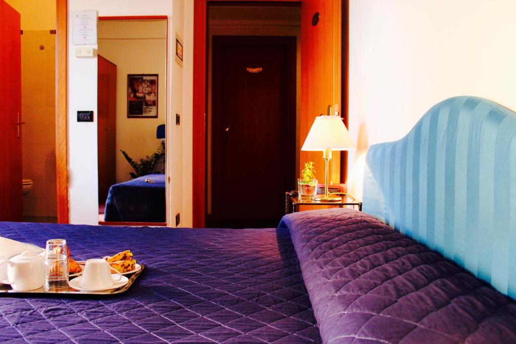 里米尼Arcangelo Roof Hotel的紫色的床,上面有盘子