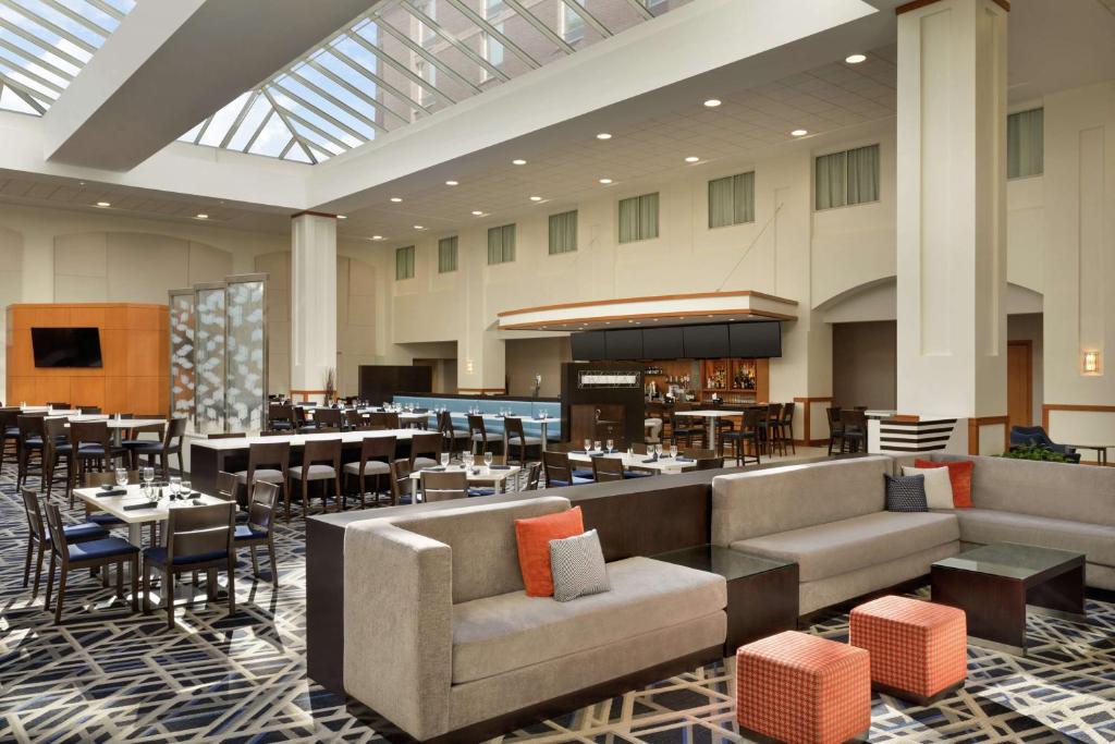波士顿波士顿洛根机场使馆套房酒店的酒店大堂设有带桌椅的餐厅