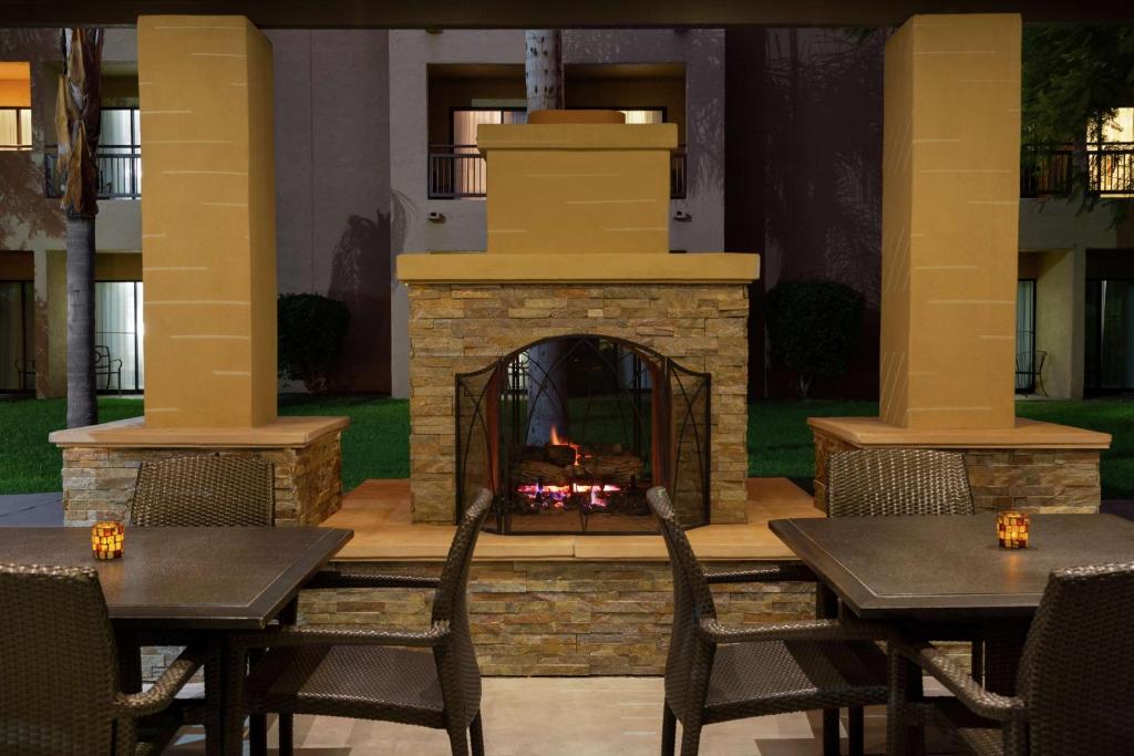 坦培Embassy Suites by Hilton Phoenix Tempe的庭院设有壁炉、桌椅