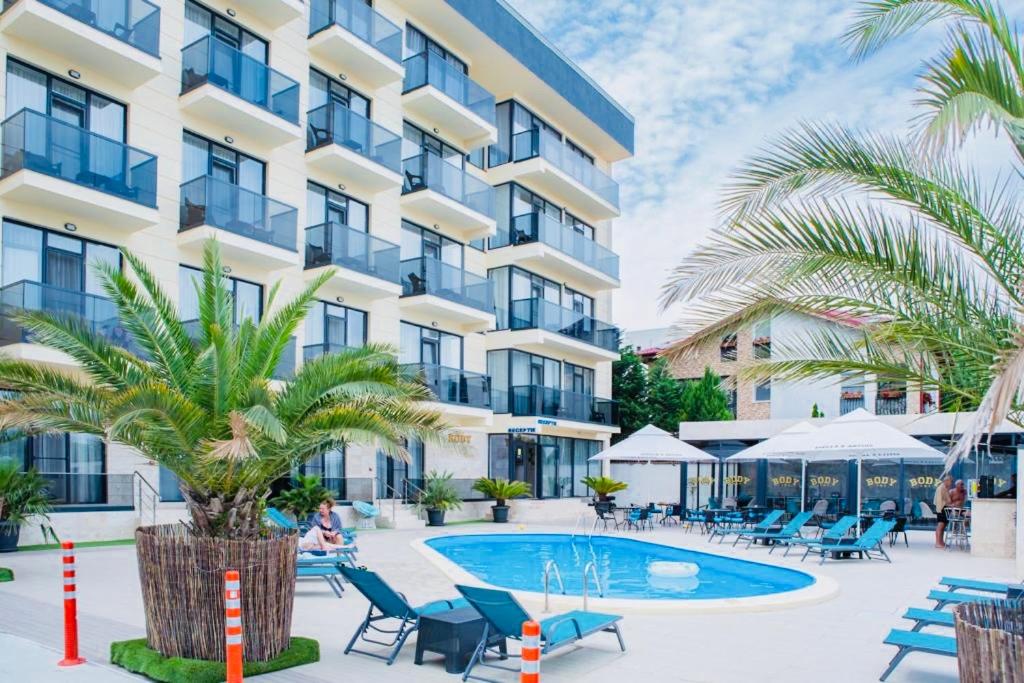 北马马亚-讷沃达里Body Hotel的享有酒店外景,设有游泳池和棕榈树