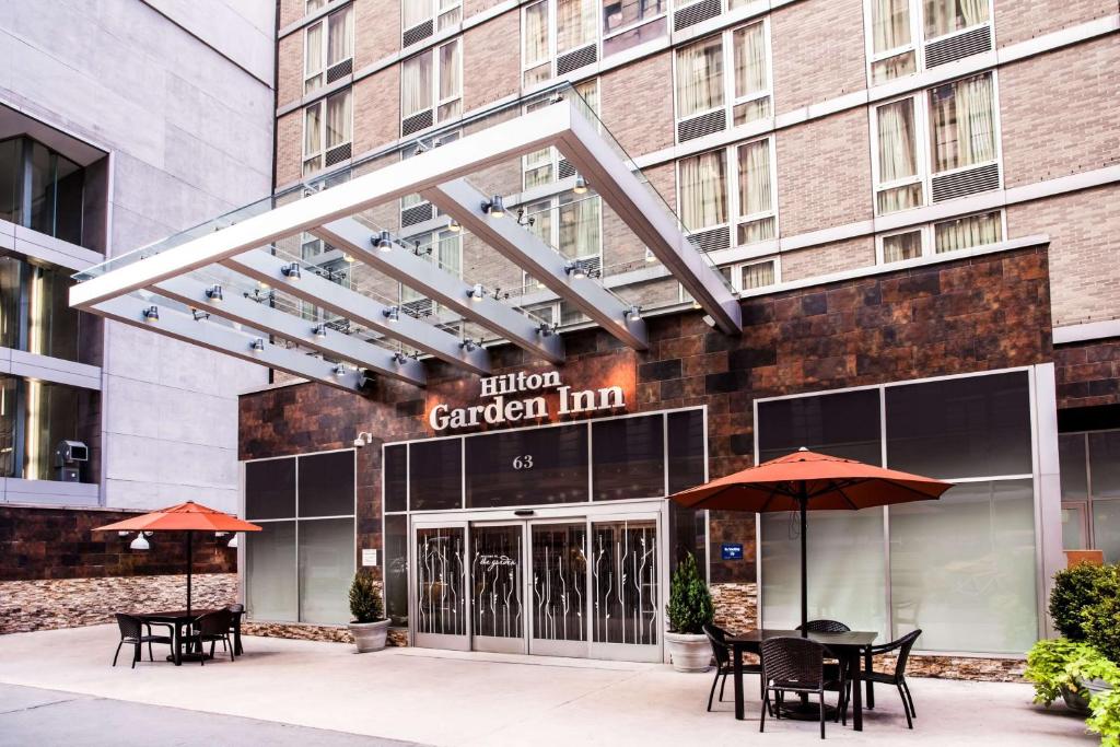 纽约西35街希尔顿花园旅馆的酒店花园旅馆前面设有桌子和遮阳伞。