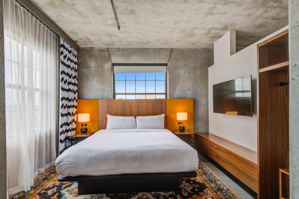 普莱诺NYLO Dallas Plano Hotel, Tapestry Collection by Hilton的一间卧室设有一张大床和一个大窗户