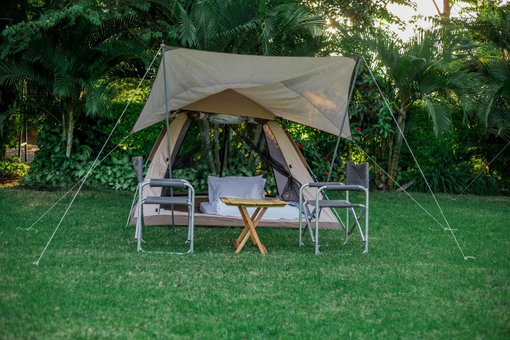 ShiriShose Campsite的草顶帐篷,配有两把椅子和一张桌子