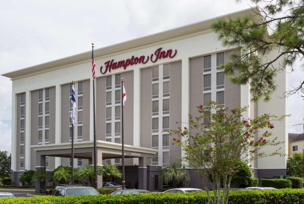 奥兰多Hampton Inn Orlando-International Airport的前面有两面旗帜的办公楼