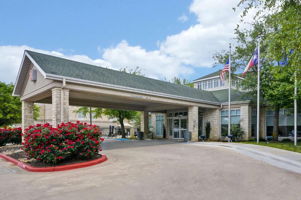 圆石城Hilton Garden Inn Austin Round Rock的前面有旗帜和鲜花的建筑