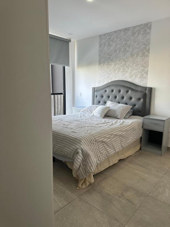 圣萨尔瓦多Paradise Apartment的一间卧室配有一张大床和灰色床头板