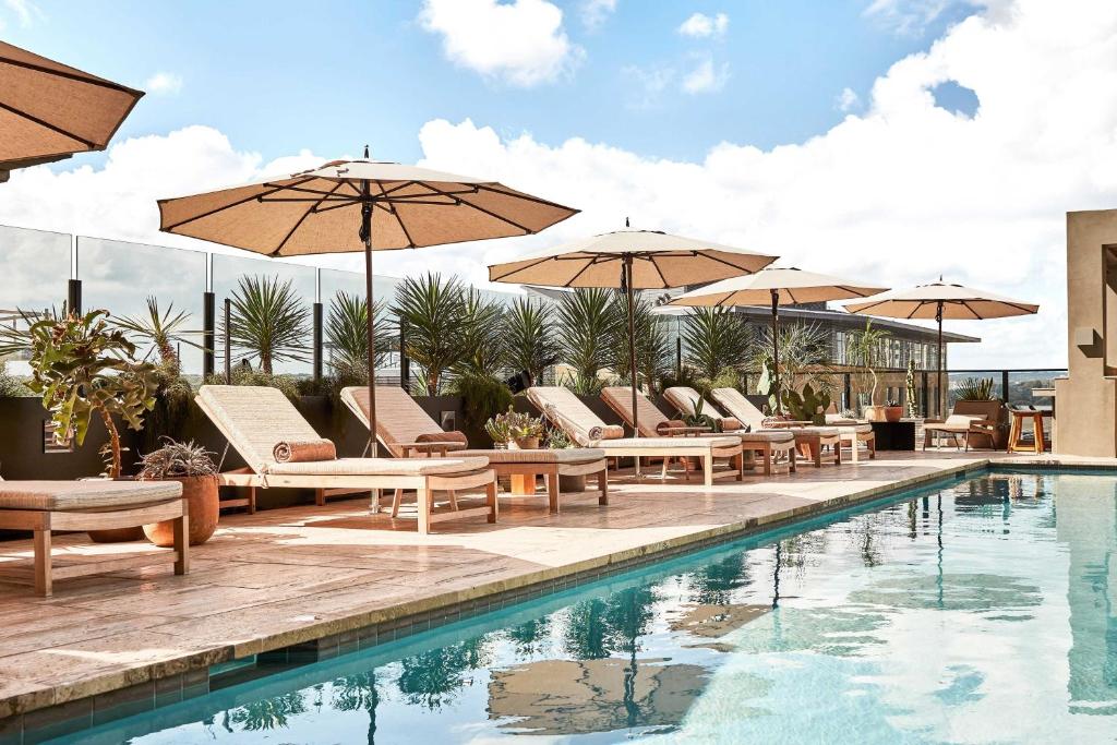 奥斯汀Austin Proper Hotel, a Member of Design Hotels的游泳池旁的游泳池配有椅子和遮阳伞