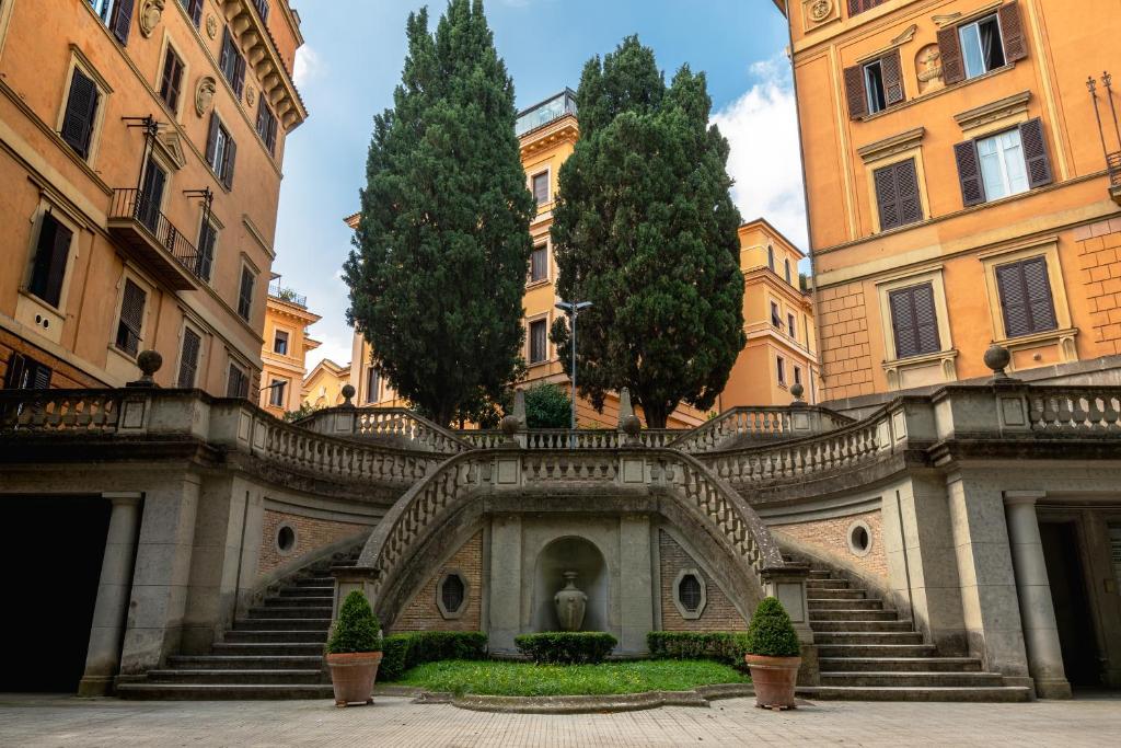 罗马Luxury Borghese Magnolia Suite的庭院中一座带楼梯和树木的建筑