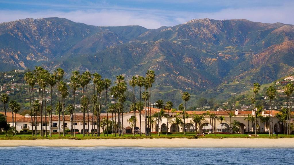 圣巴巴拉圣巴巴拉海滨度假希尔顿酒店的棕榈树和山脉为背景的度假胜地