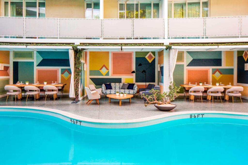 洛杉矶Avalon Hotel Beverly Hills, a Member of Design Hotels的一座酒店,旁边设有游泳池和桌椅