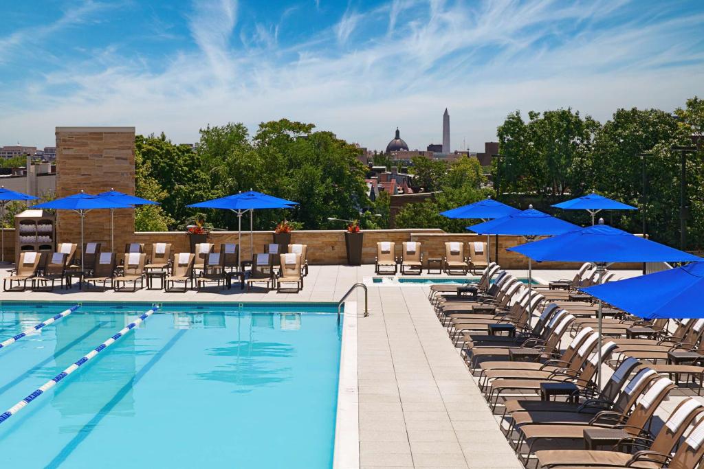 华盛顿华盛顿希尔顿酒店的屋顶游泳池配有椅子和蓝色遮阳伞