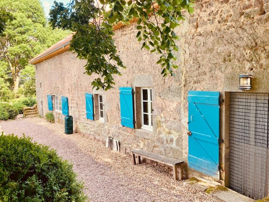 BrassyRuime woning in de Morvan, Bourgogne met seizoensgebonden zwembad的一座建筑,设有蓝色的门和旁边的一个长凳