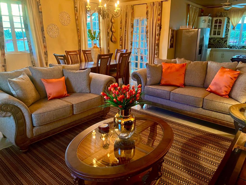 ArimaPearls Place的客厅配有沙发和鲜花桌