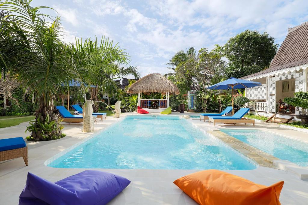 沙努尔Puri Tempo Doeloe Boutique Hotel的度假村的游泳池配有椅子和遮阳伞