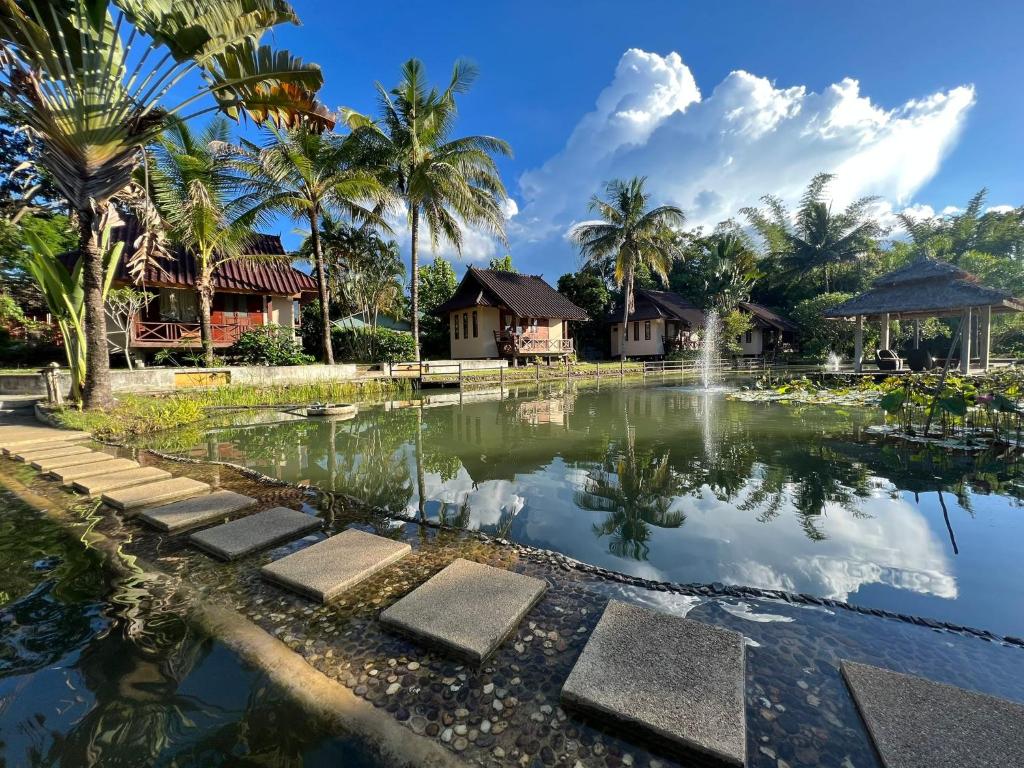 拜县Pairadise Hotel的棕榈树度假村前的池塘