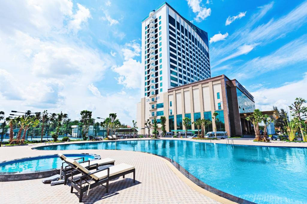 芹苴芹苴孟清奢华酒店的酒店游泳池的背景是一座高高的建筑