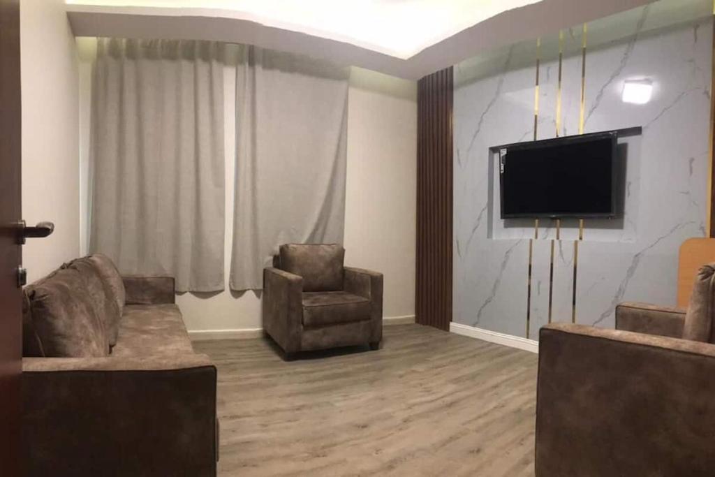 麦地那Hayat Al madinah Hotel فندق حياة المدينة的客厅配有2把椅子和平面电视