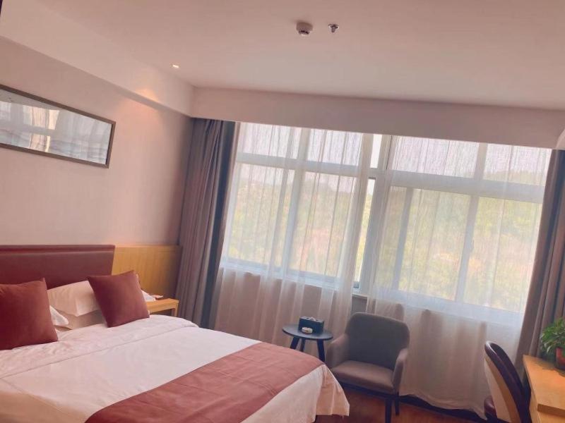 Taozhuang格丽枣庄高铁站酒店的一间卧室设有一张床和一个大窗户