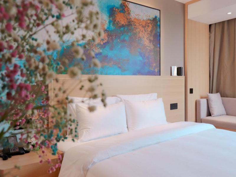 阜阳格菲阜阳市火车站北京东路酒店的卧室配有一张床,墙上挂有绘画作品