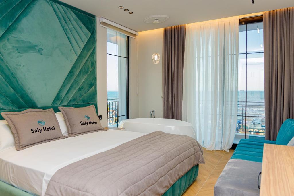都拉斯Hotel Saly的酒店客房设有一张床、一个浴缸和窗户。