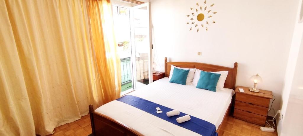 雅典Cozy room in quiet neighbourhood的一间卧室配有一张带蓝色枕头的床和一扇窗户。