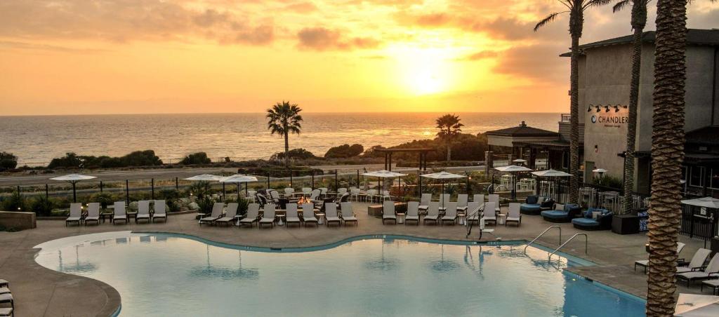 卡尔斯巴德Cape Rey Carlsbad Beach, A Hilton Resort & Spa的一座带游泳池和椅子的酒店,以及大海