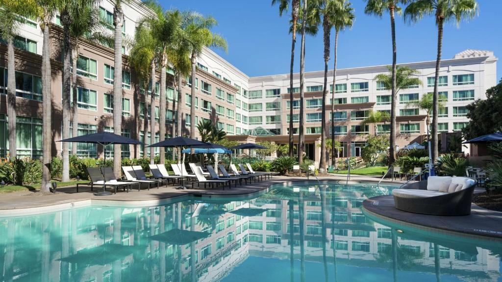 圣地亚哥DoubleTree by Hilton San Diego Del Mar的一座带椅子和棕榈树的度假游泳池和一座建筑
