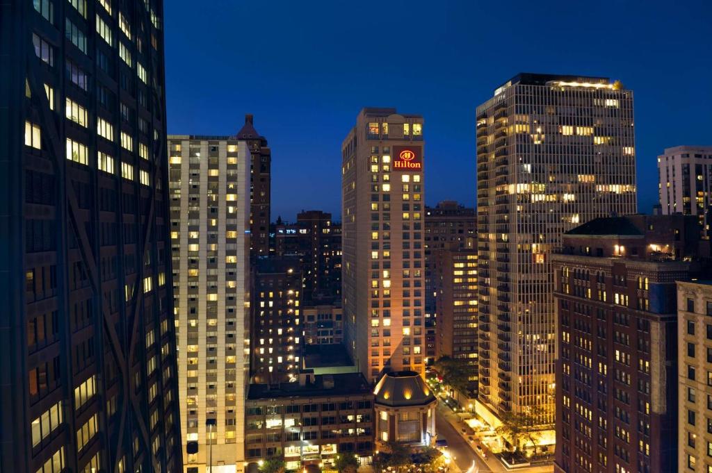 芝加哥Hilton Chicago Magnificent Mile Suites的城市天际线,晚上有高楼