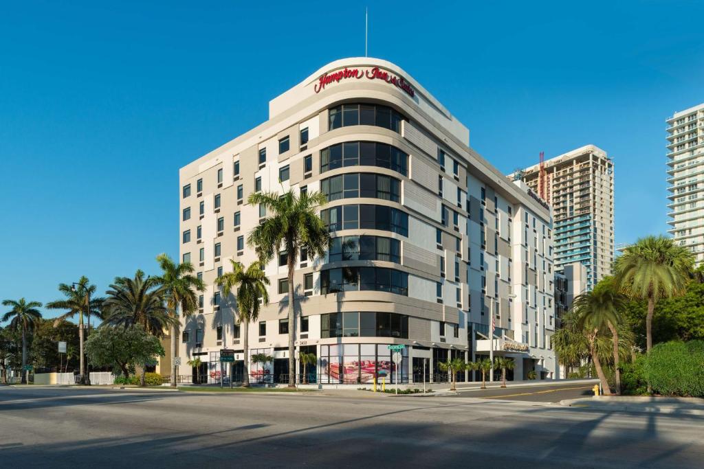 迈阿密Hampton Inn & Suites Miami Wynwood Design District, FL的一座高大的白色建筑,前面有棕榈树
