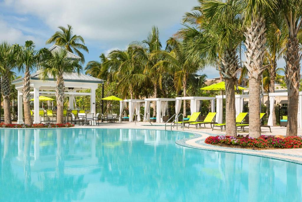 基韦斯特基韦斯特/基斯系列希尔顿花园酒店的度假村的游泳池,种植了棕榈树,配有椅子