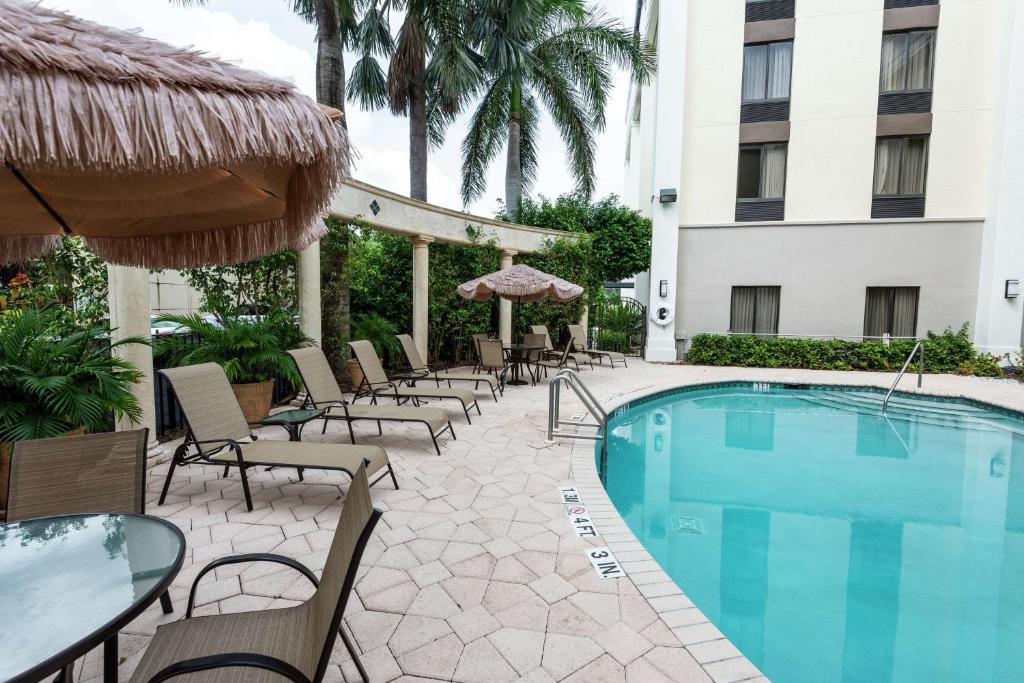布卡拉顿博卡拉顿汉普顿酒店的酒店旁的游泳池配有椅子和遮阳伞