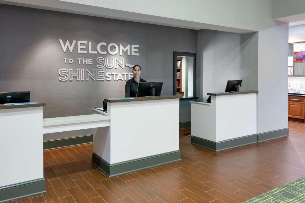 奥兰多汉普顿酒店 - 奥兰多机场村庄通道的坐在沙龙迎宾台上的女人