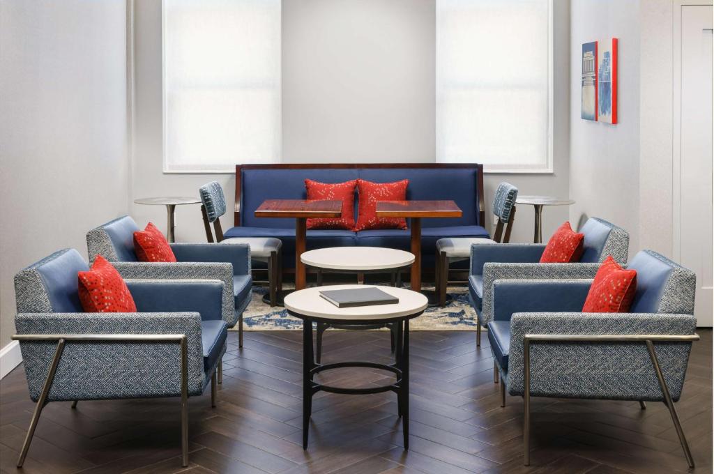 华盛顿Hampton Inn Washington DC White House的一间设有椅子和桌子及红色枕头的等候室
