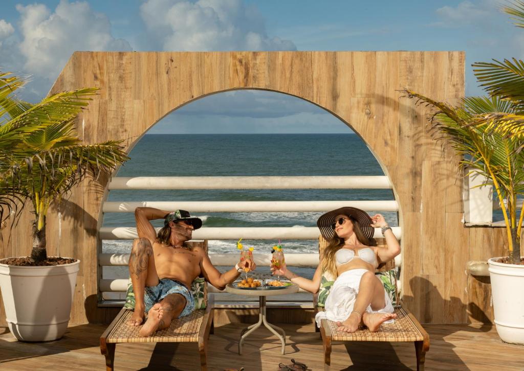 伊列乌斯奥帕巴普拉亚酒店的坐在海滩桌子上的男人和女人