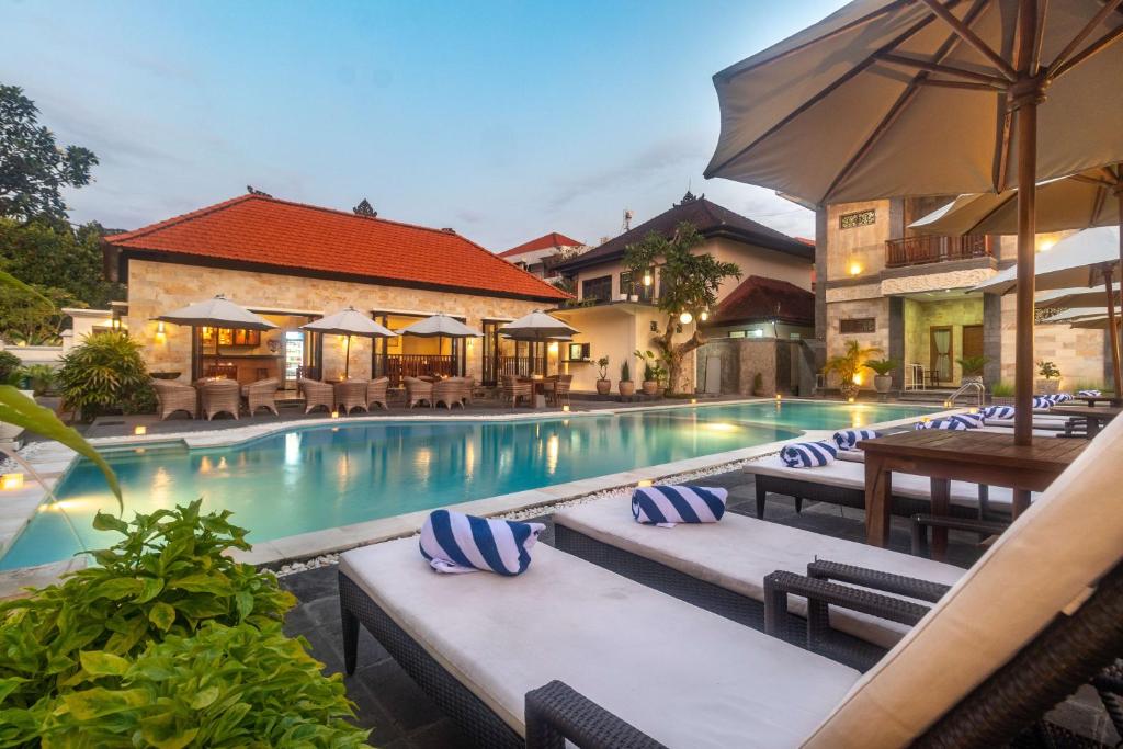 沙努尔塞嘉拉阿贡酒店的一个带躺椅和遮阳伞的游泳池