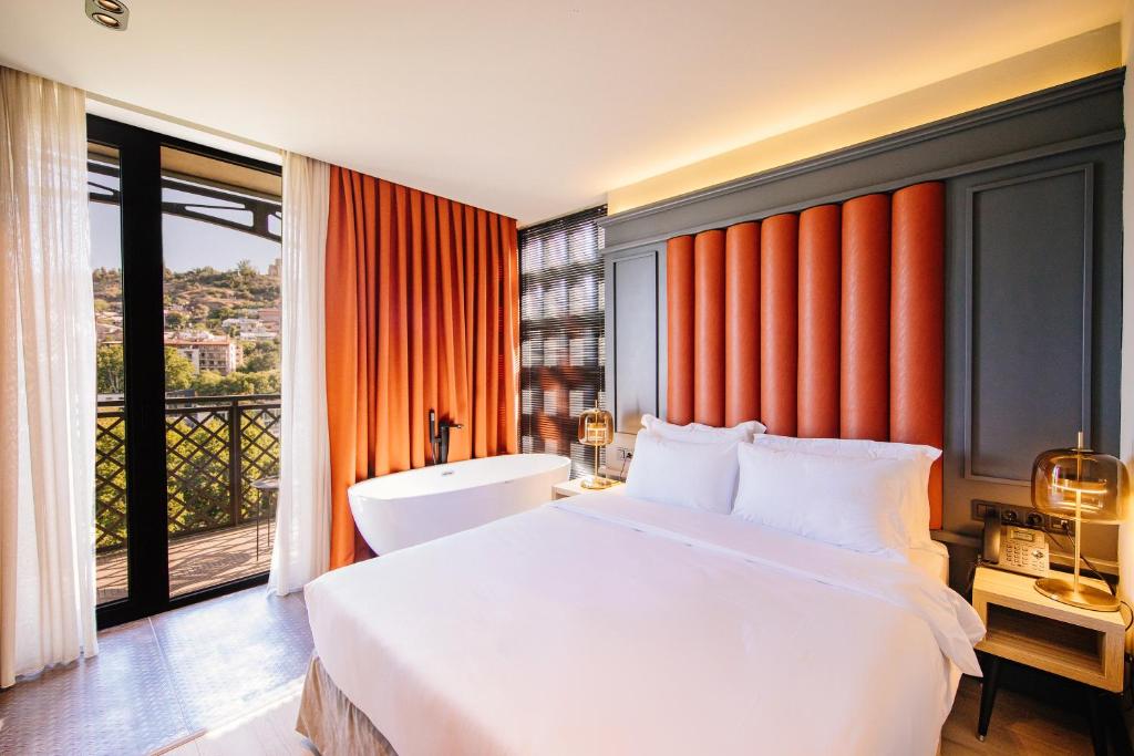 第比利斯Sandali Metekhi Boutique Hotel的一间卧室设有一张大床和一个大窗户