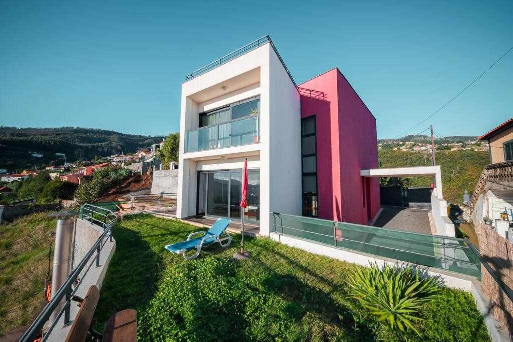 丰沙尔Casa da Terça Nice View and Parking的红白色房子,草地上摆放着蓝色椅子