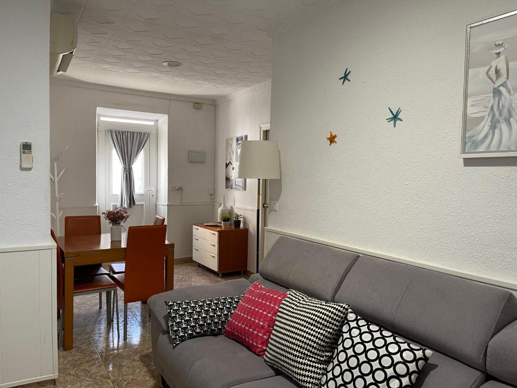圣卡洛斯拉腊皮塔Lleida 25, casa de poble a planta baixa amb àmplia terrassa equipada的客厅配有带枕头的灰色沙发