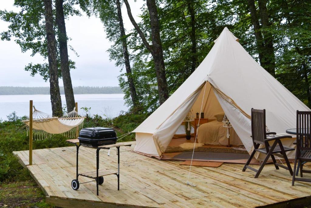 OdensjöGlamping Bolmen, Seaview, free canoe的一个带吊床和烧烤架的白色帐篷