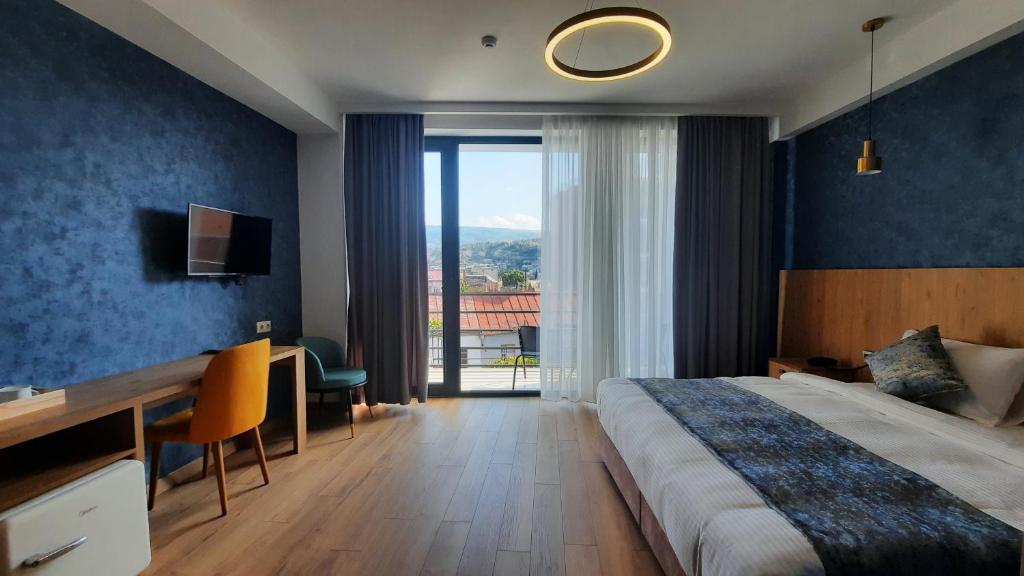 第比利斯Hotel DownTown Avlabari的配有一张床、一张书桌和一扇窗户的酒店客房