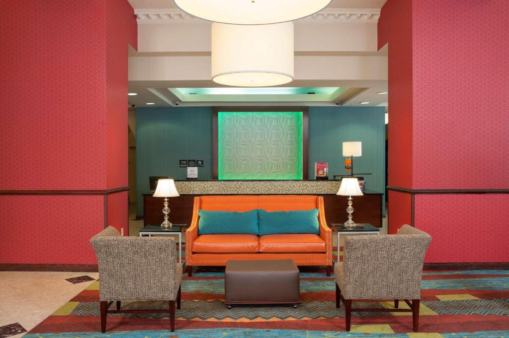 印第安纳波利斯印第安纳波利斯市中心希尔顿恒庭酒店（瑟科中心对面）的一张橙色的沙发,房间带两把椅子