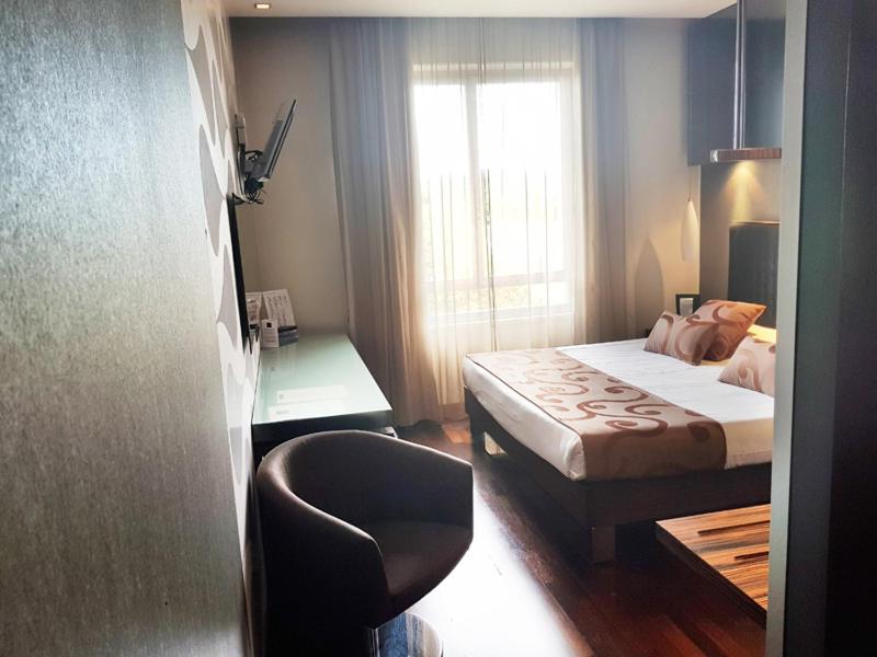 坎图Axolute Comfort Hotel Como - Cantù的卧室配有床、椅子和窗户。
