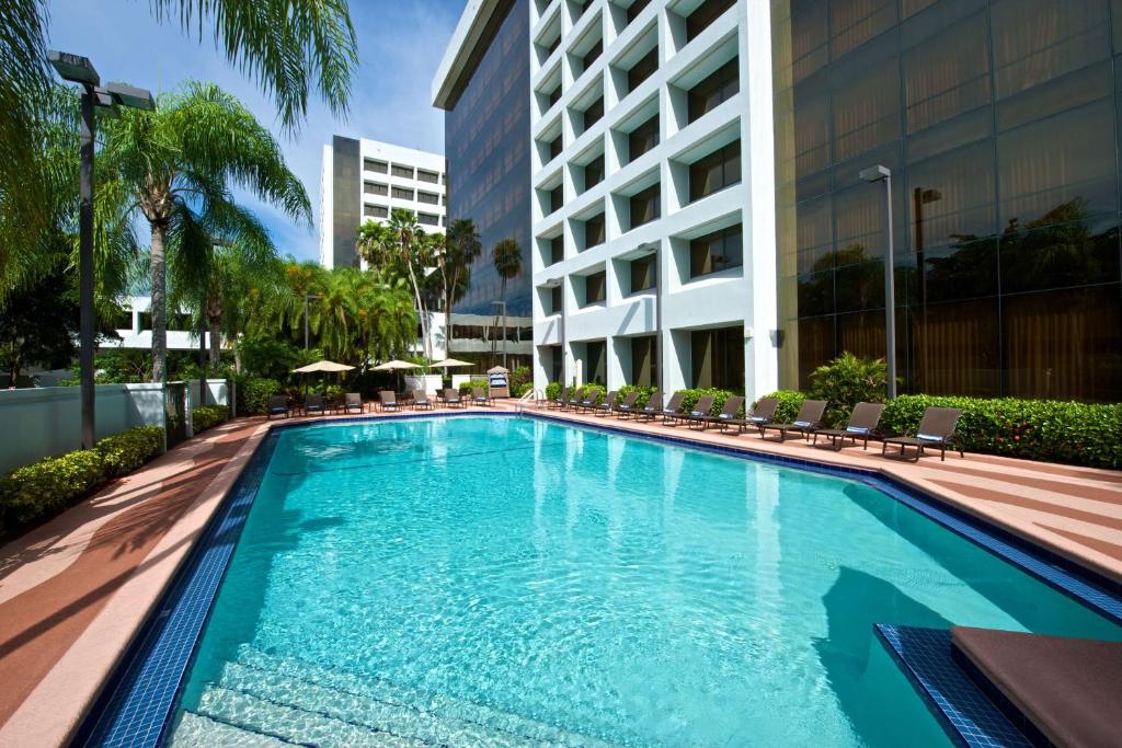 棕榈滩花园Embassy Suites by Hilton Palm Beach Gardens PGA Boulevard的一座带椅子的游泳池以及一座建筑