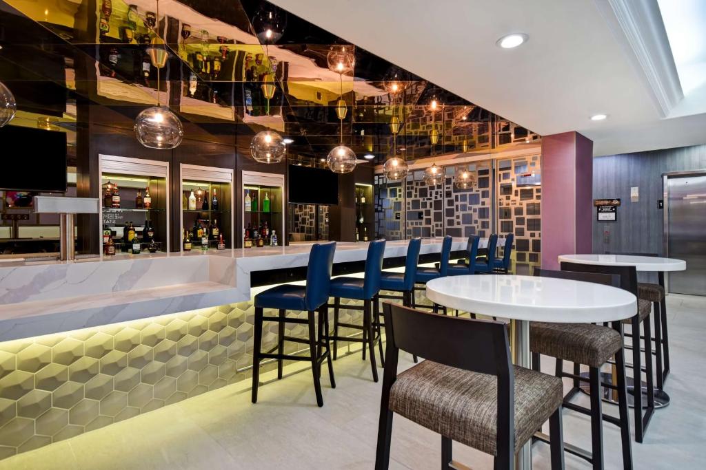 皇后区Hampton Inn NY-JFK的餐厅设有酒吧,配有蓝色的桌椅