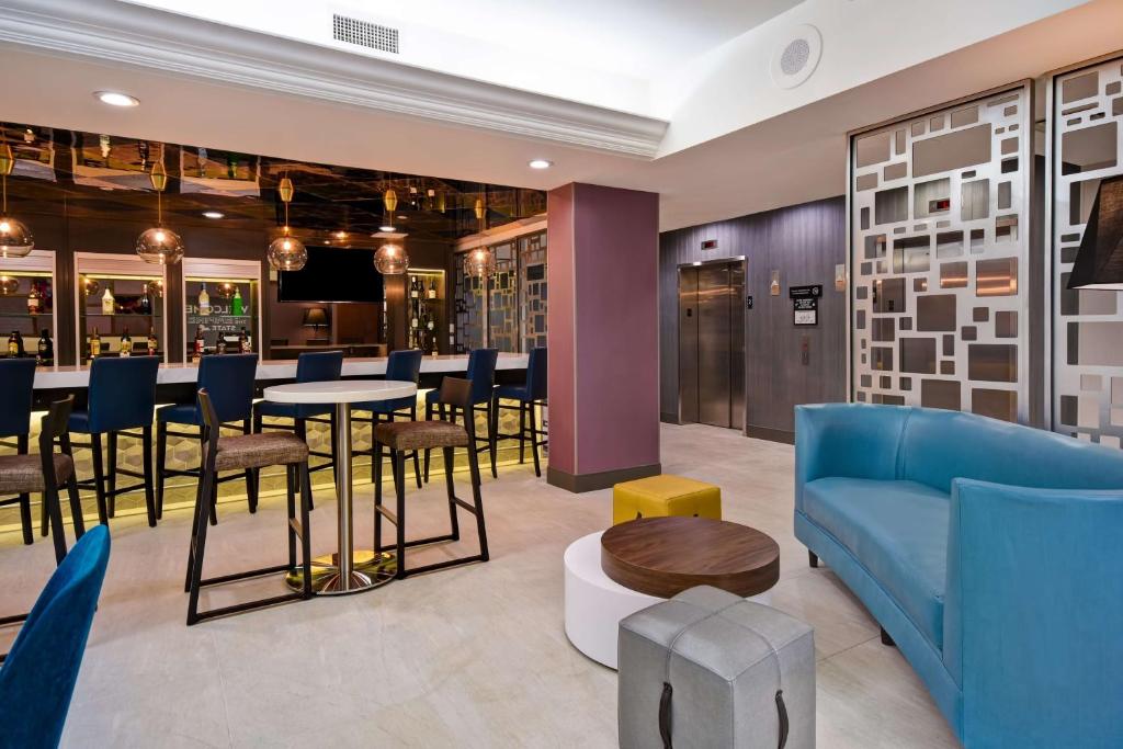 皇后区Hampton Inn NY-JFK的大厅里有一张蓝色的沙发和一张桌子和几把椅子